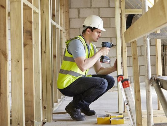 hausbau-haus-bauen-eigenleistung-handwerker-dach-05 Bauarbeiter verschraubt Holzplanken