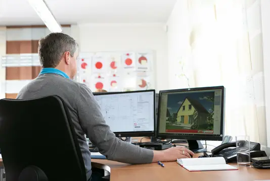 Mann vor zwei Computerbildschirmen